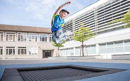 boy jumping on playground trampoline